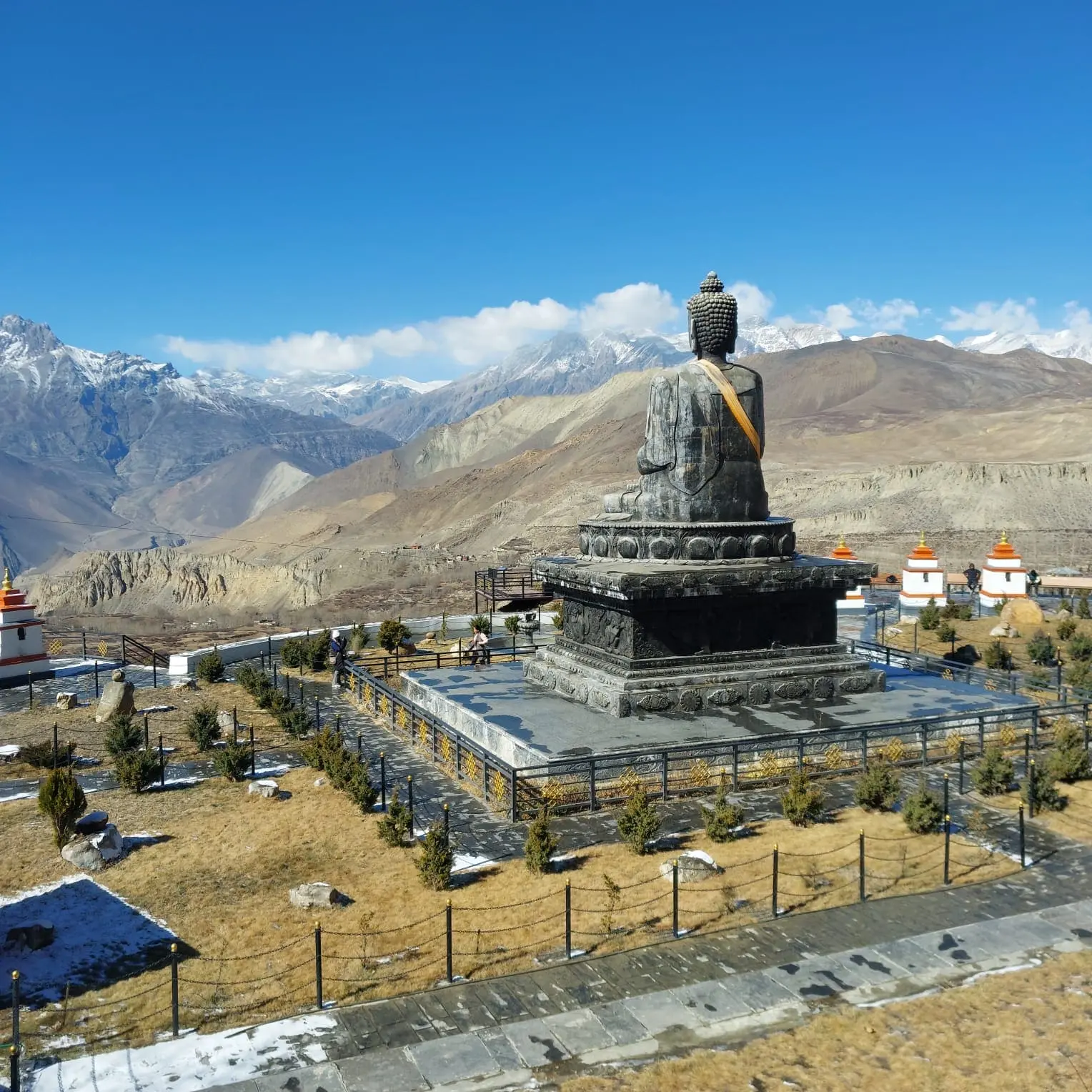 Lord Buddha statue at Muktinath Temple, Mustang, Nepal, surrounded by prayer flags and devotees paying respect.