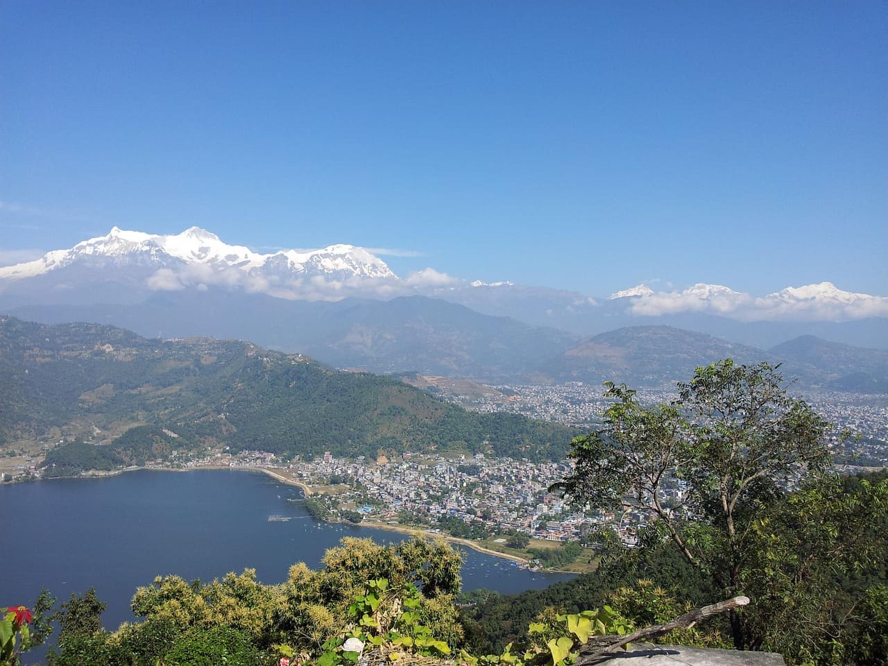 Majestic Annapurna mountain range viewed from Pokhara, with snow-capped peaks shining above lush green hills and clear skies.