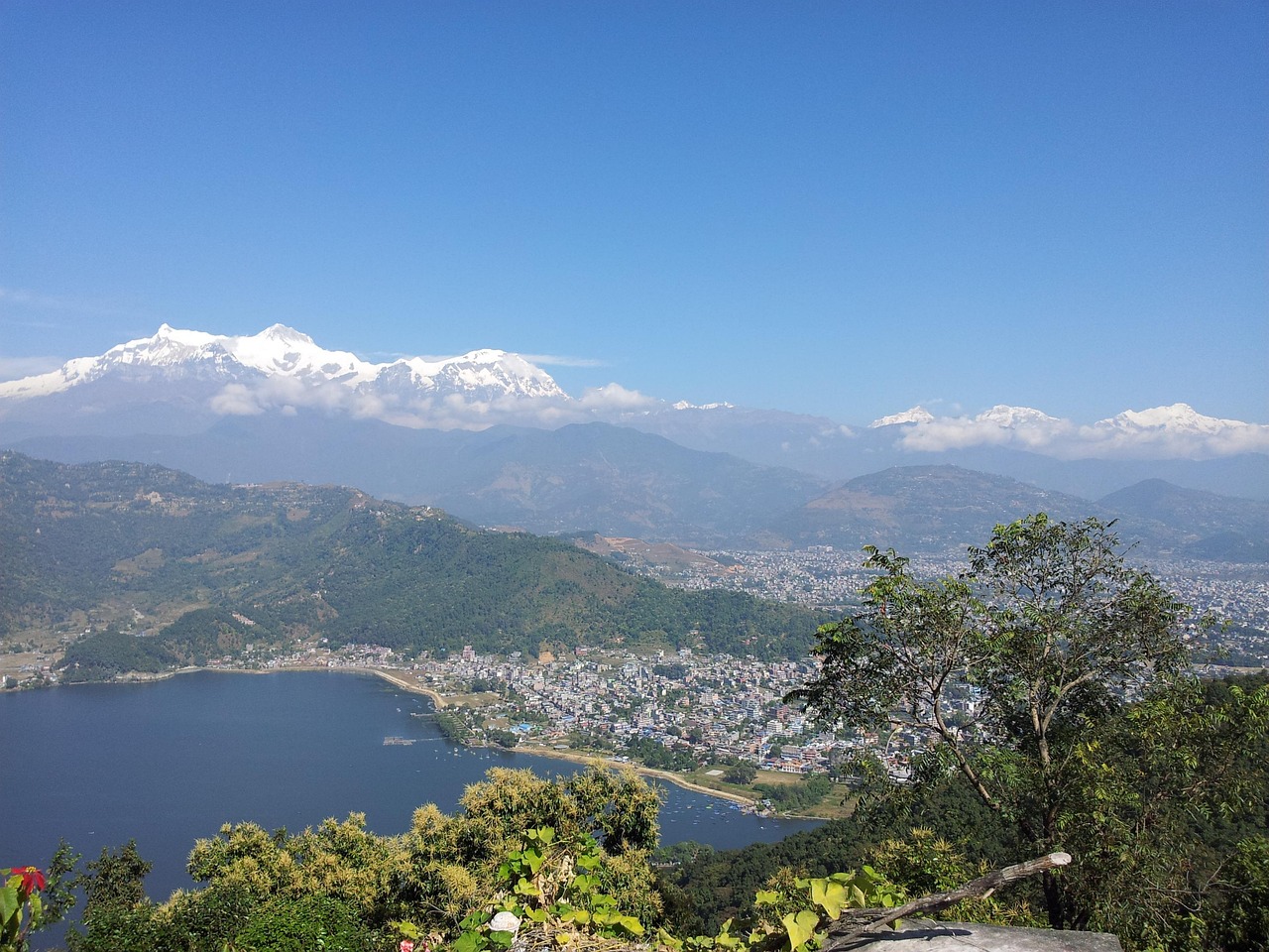 Panoramic view of the Annapurna mountain range as seen from Pumdikot viewpoint, with clear skies and lush hills in the foreground.
