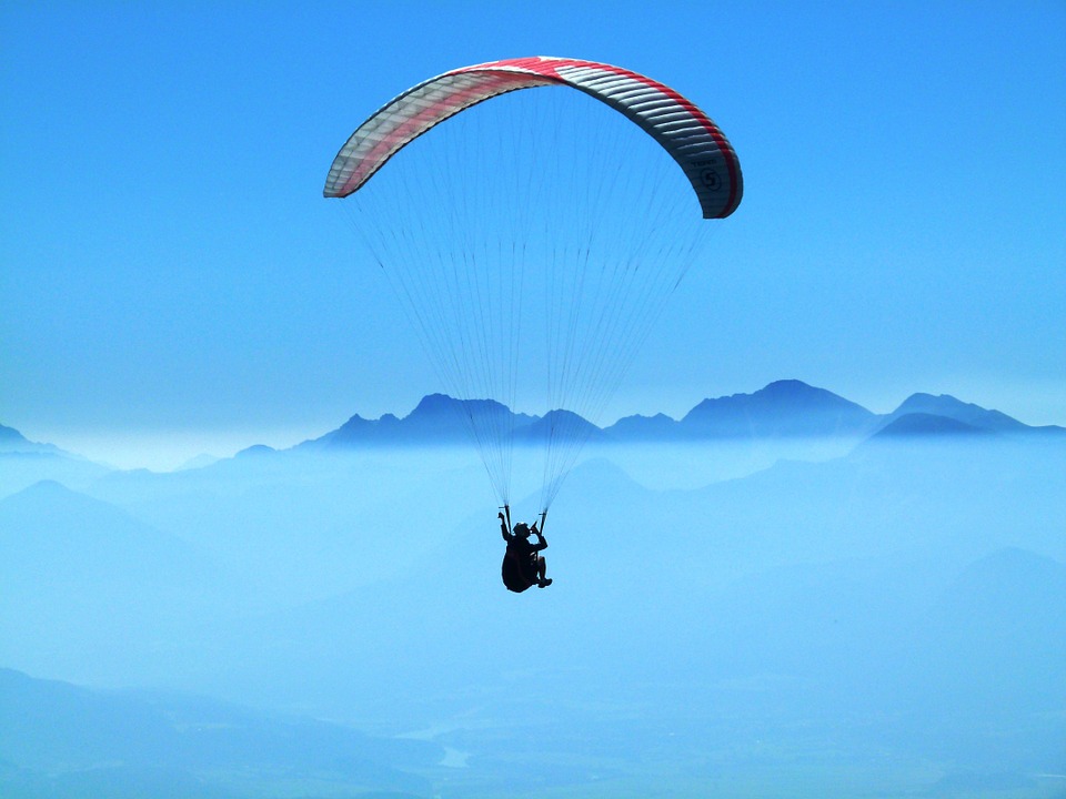 Paraglider soaring over Pokhara Valley with stunning views of Phewa Lake and Annapurna mountains in the background.