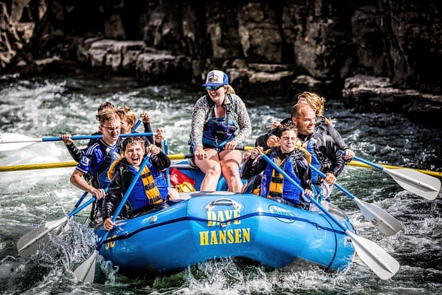 People enjoying an exciting river rafting experience on the Sun Koshi River, paddling through white-water rapids surrounded by natural greenery.