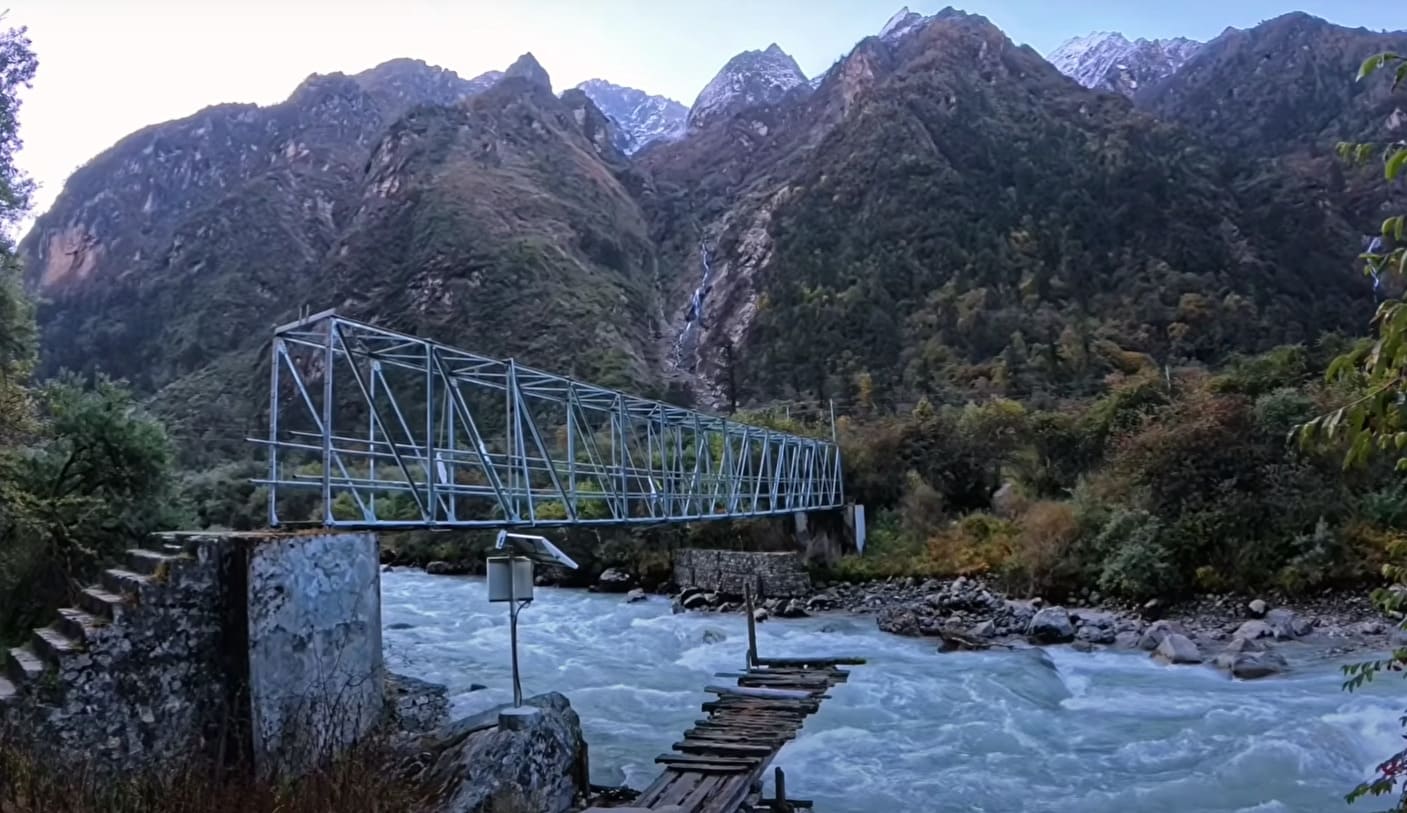 Trishuli River flowing alongside the scenic Langtang trekking trail, surrounded by lush green hills and rocky riverbanks.