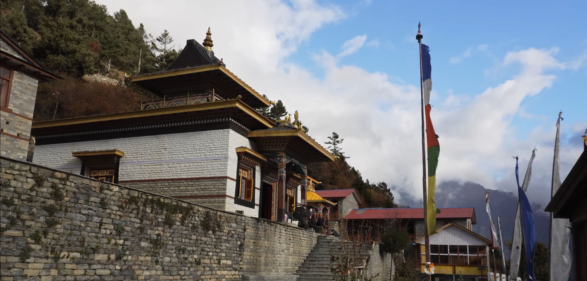 Upper Pisang Buddhist temple on hillside with prayer flags, traditional architecture, and Himalayan mountains in the background.