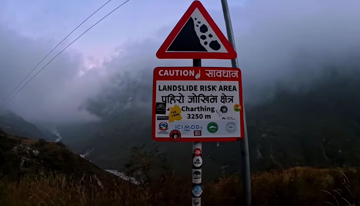 Warning board indicating a landslide-prone area along a mountain trail.